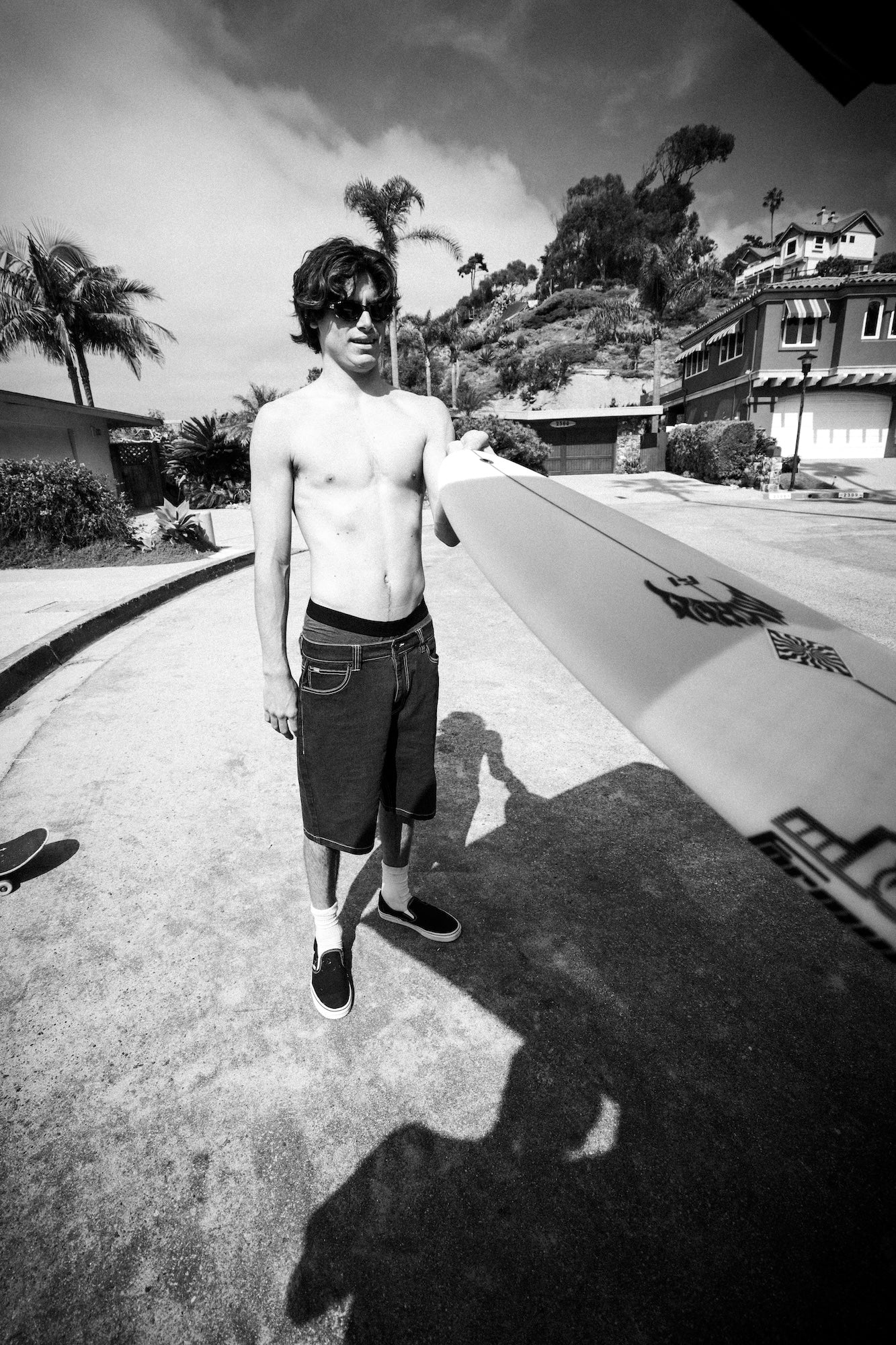 Man holding surfboard on sunny street