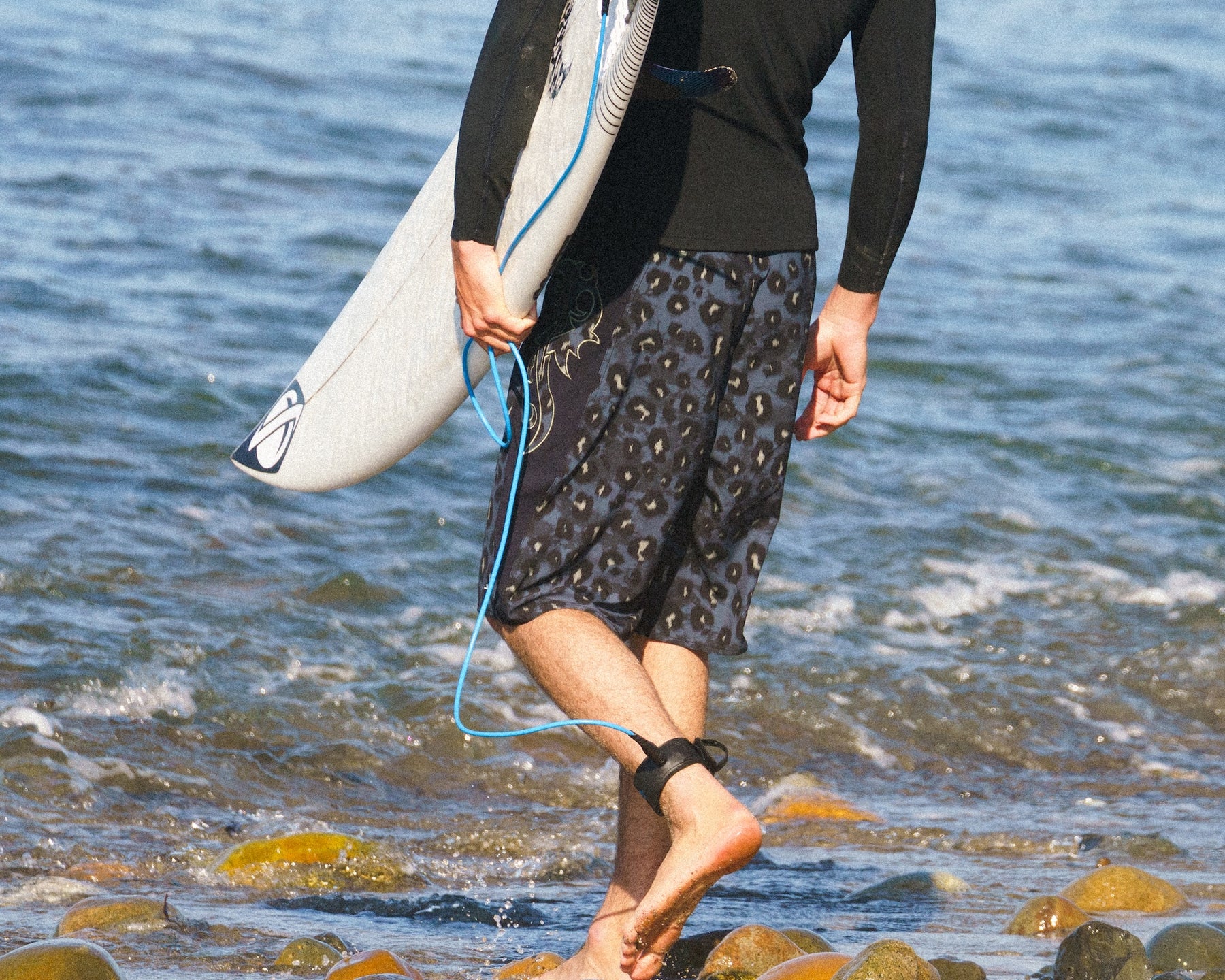 Surfer walking into the ocean with surfboard