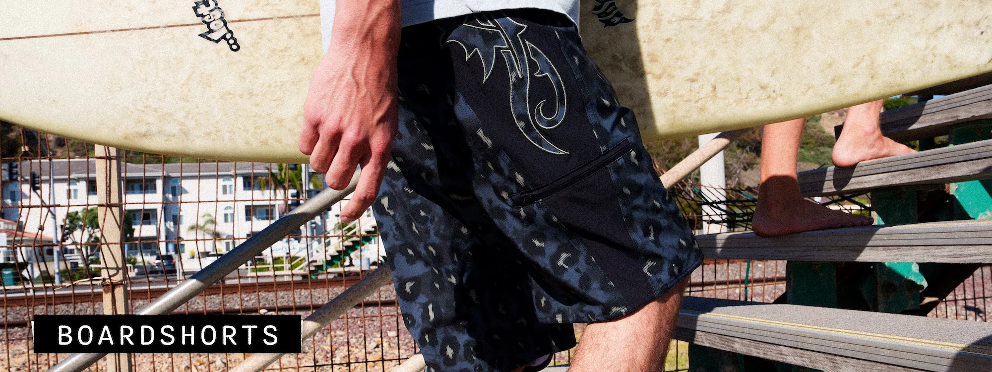 Man in boardshorts carrying a surfboard