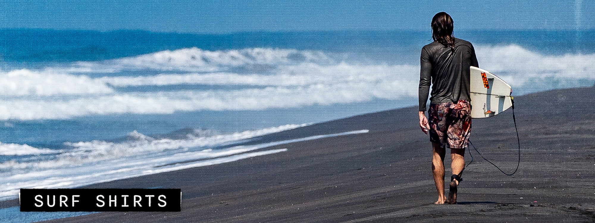 Man carrying surfboard along shoreline