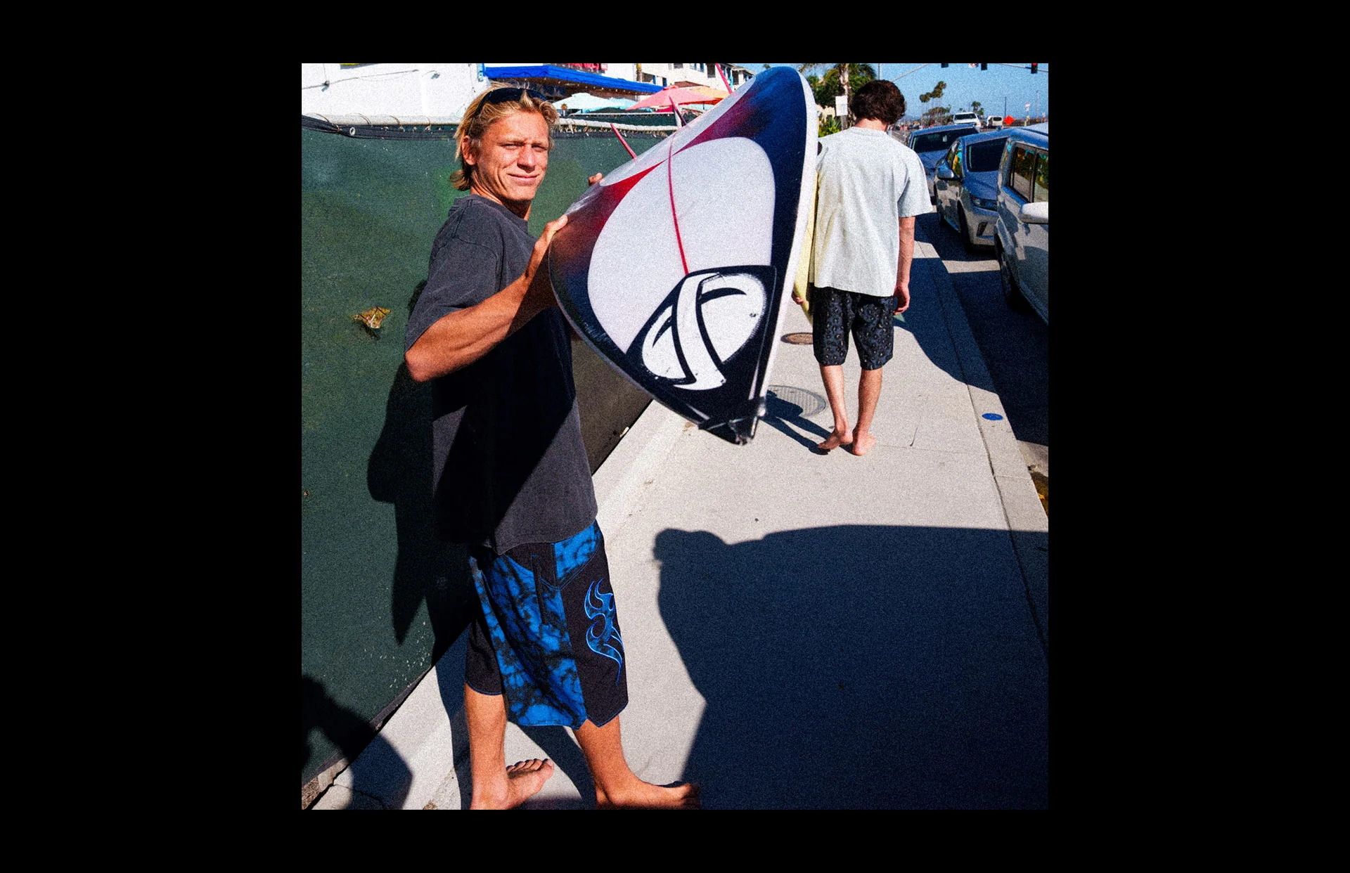 Man walking with surfboard in sunlight