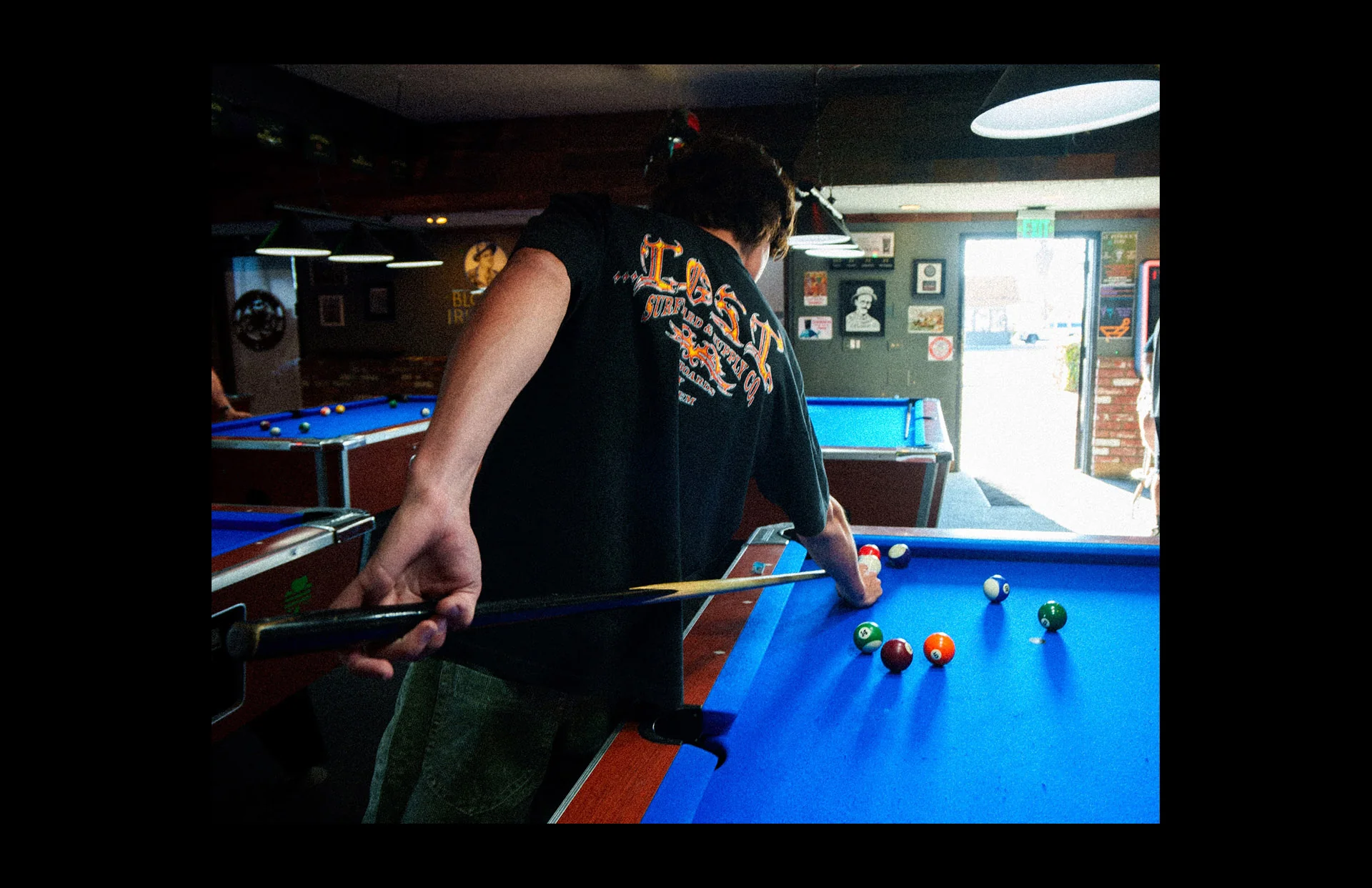 Person playing pool in dimly lit room.