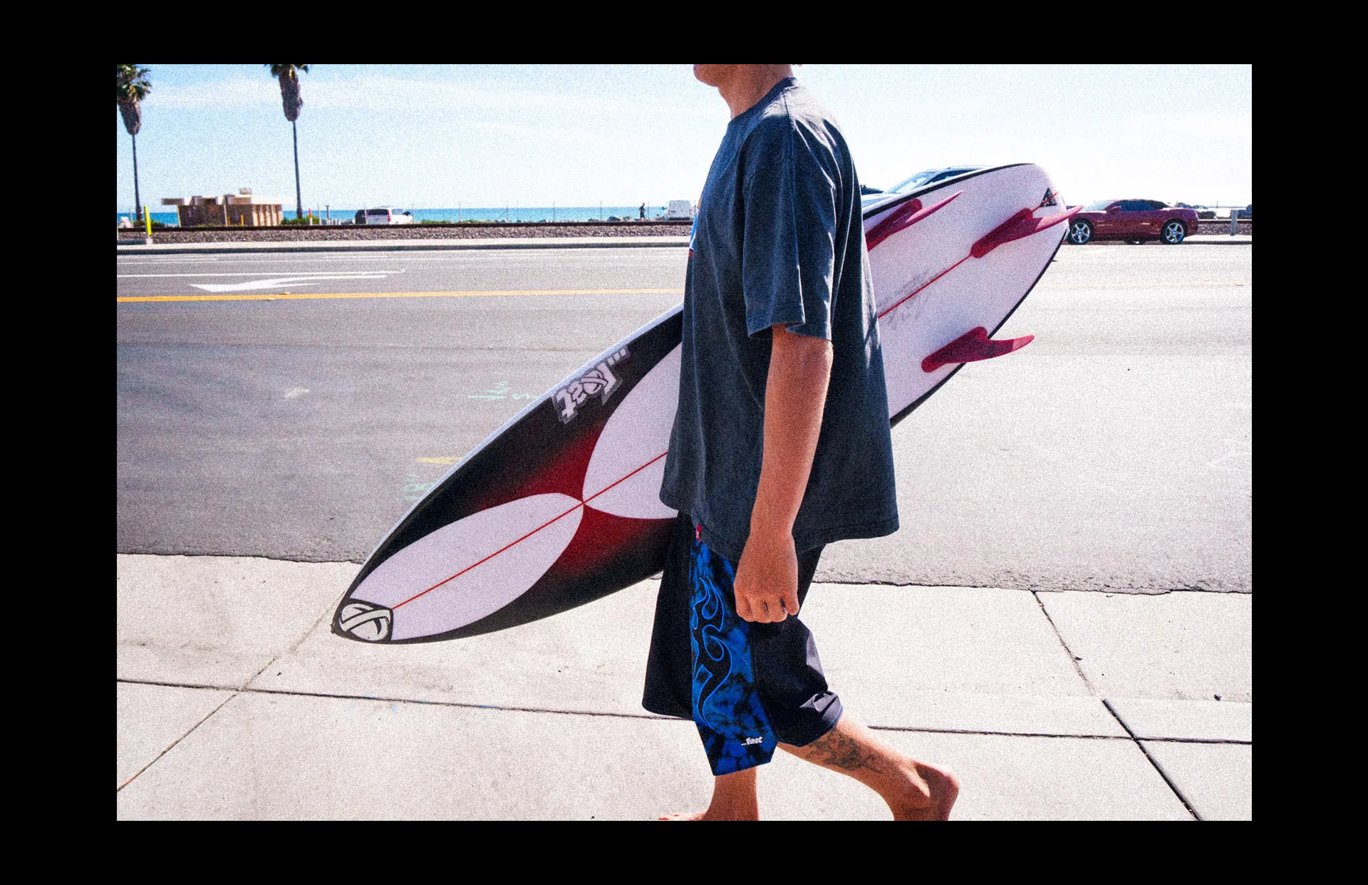 Individual holding surfboard by ocean view.