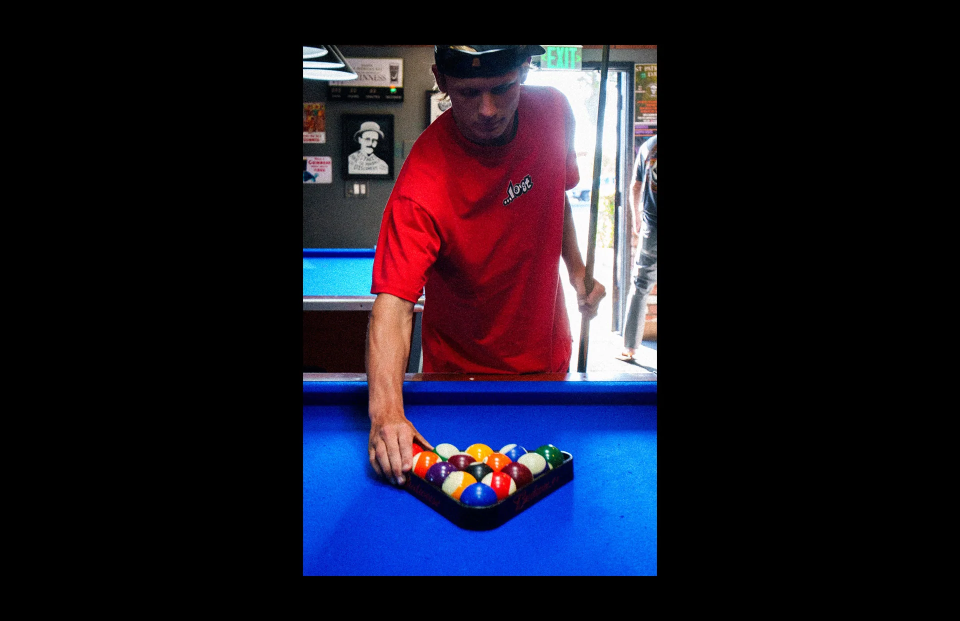 Man arranging pool balls on blue table