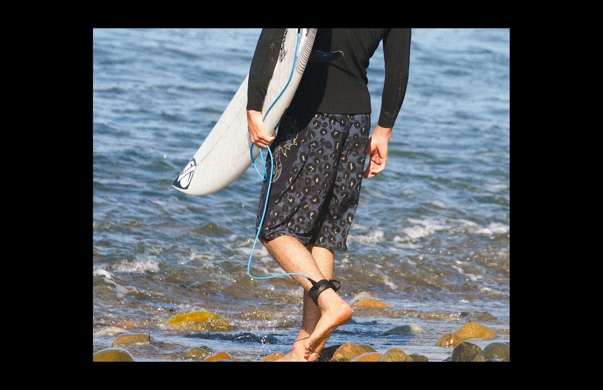 Person carrying surfboard near ocean